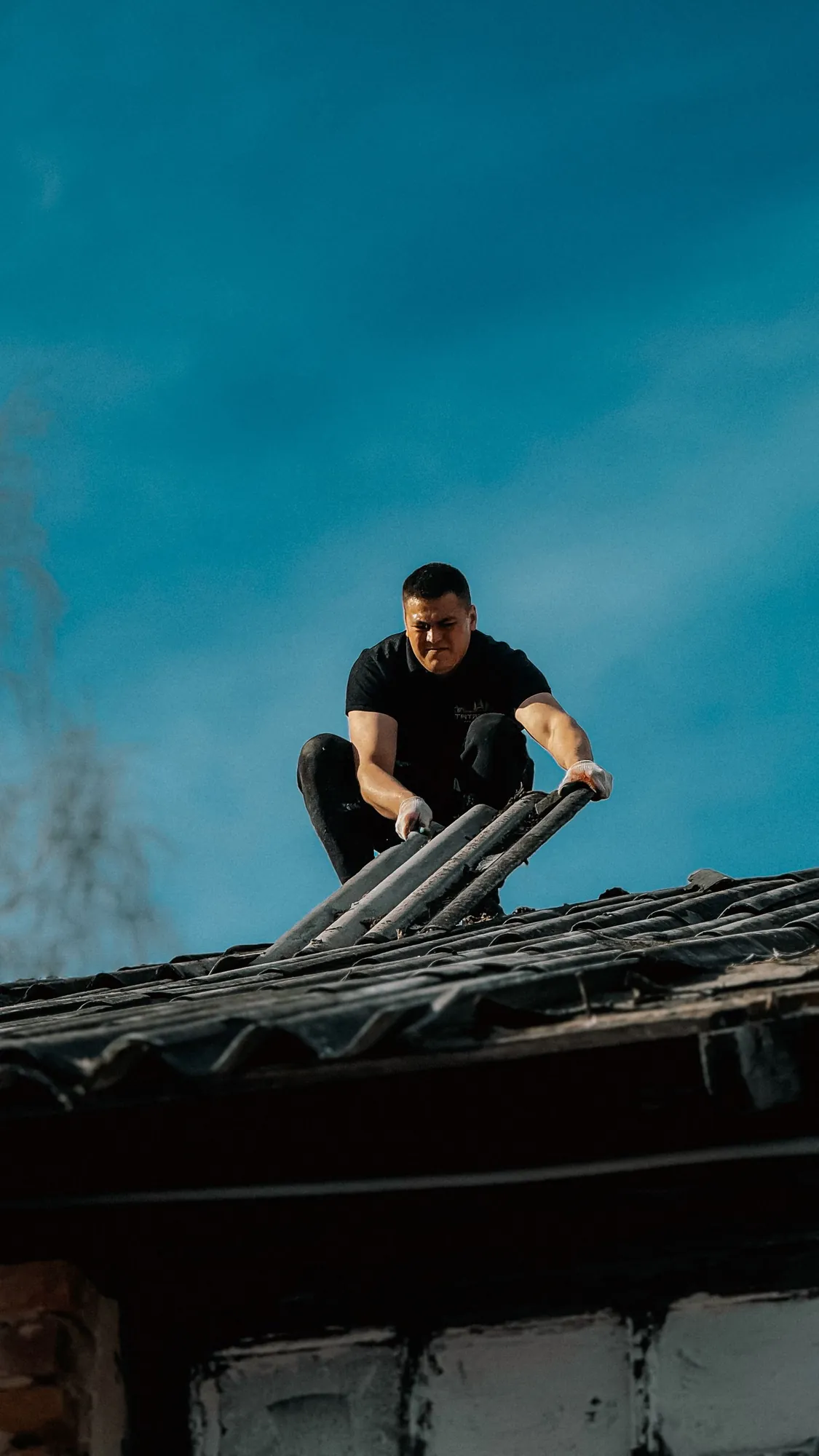 Roofer working on a roof against a blue sky